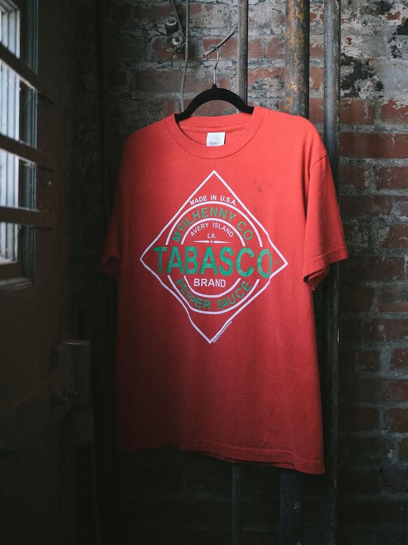 A vintage Tabasco tee shirt on a hanger against the painted brick wall at 6 Foot Closet