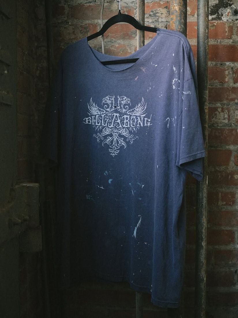 A vintage Billabong tee shirt on a hanger against the painted brick wall at 6 Foot Closet