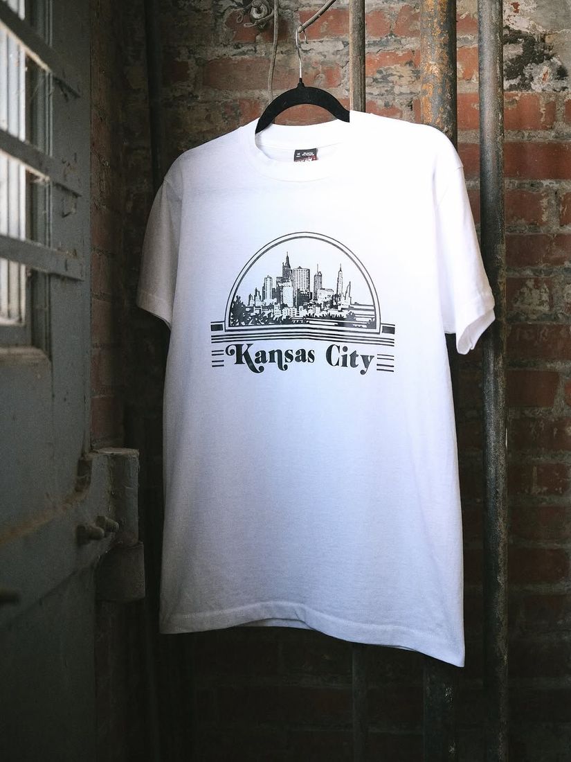 A vintage Kansas City tee shirt on a hanger against the painted brick wall at 6 Foot Closet